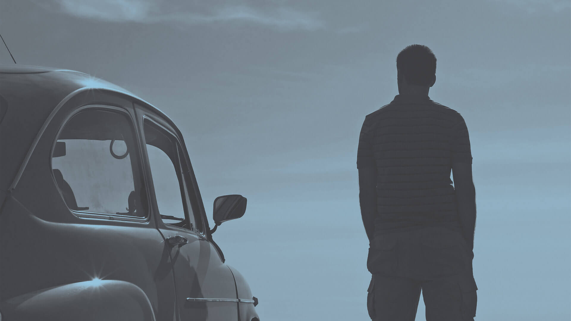 Man standing in front of car remembering his deceased loved one